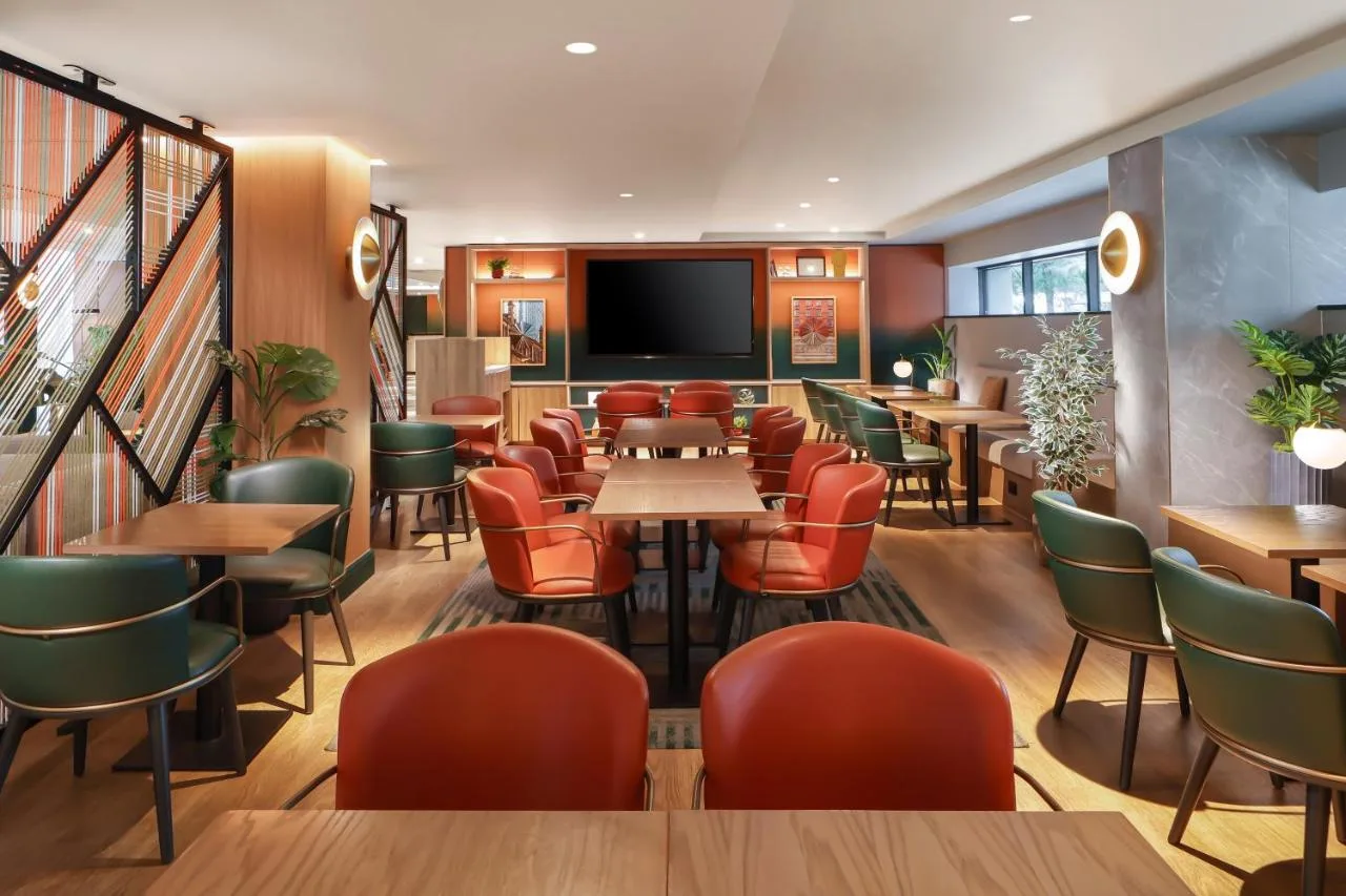 a restaurant with tables and chairs and a flat screen tv at Manchester Marriott Hotel Piccadilly in Manchester