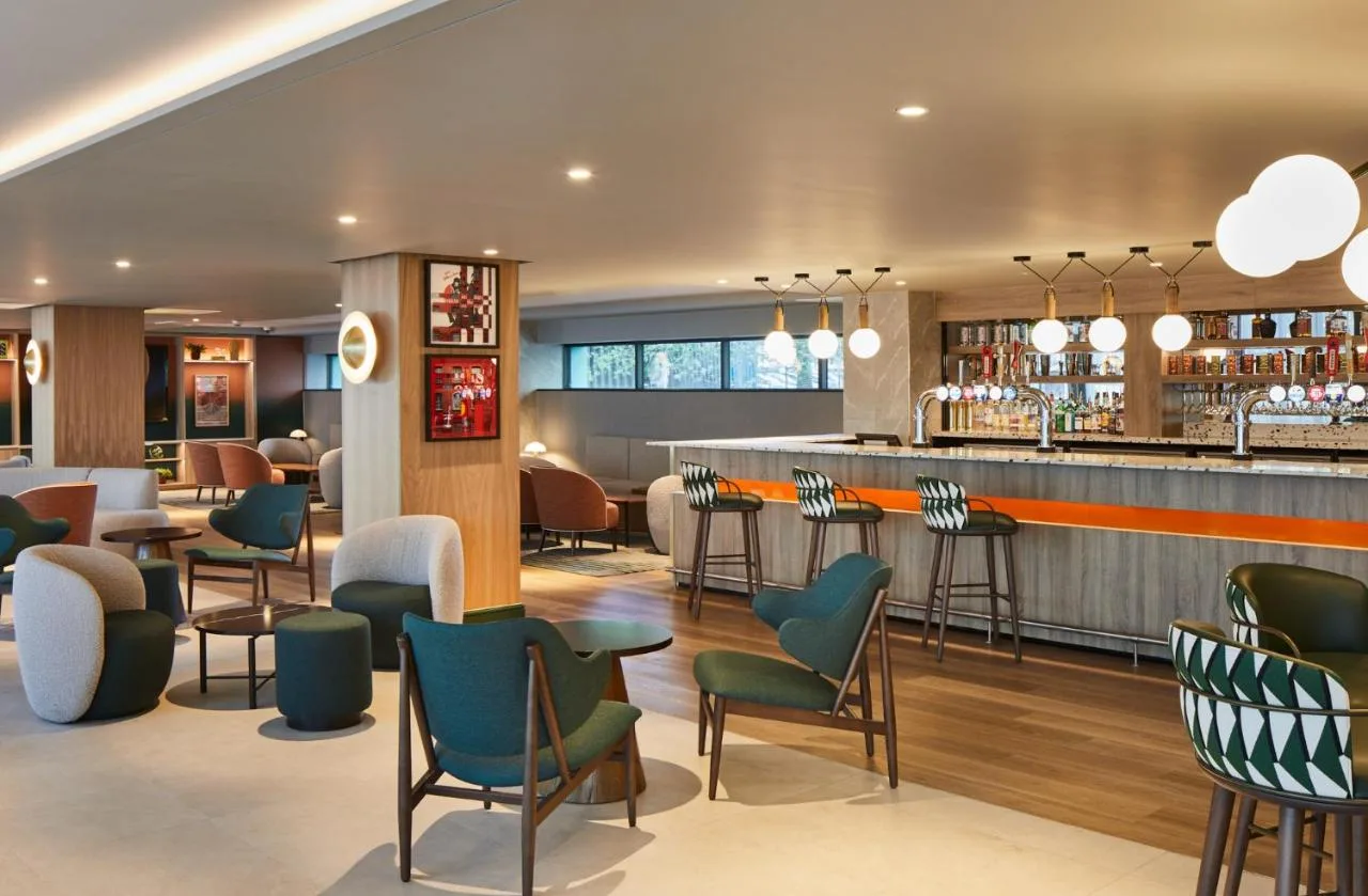 a bar in a restaurant with chairs and a counter at Manchester Marriott Hotel Piccadilly in Manchester