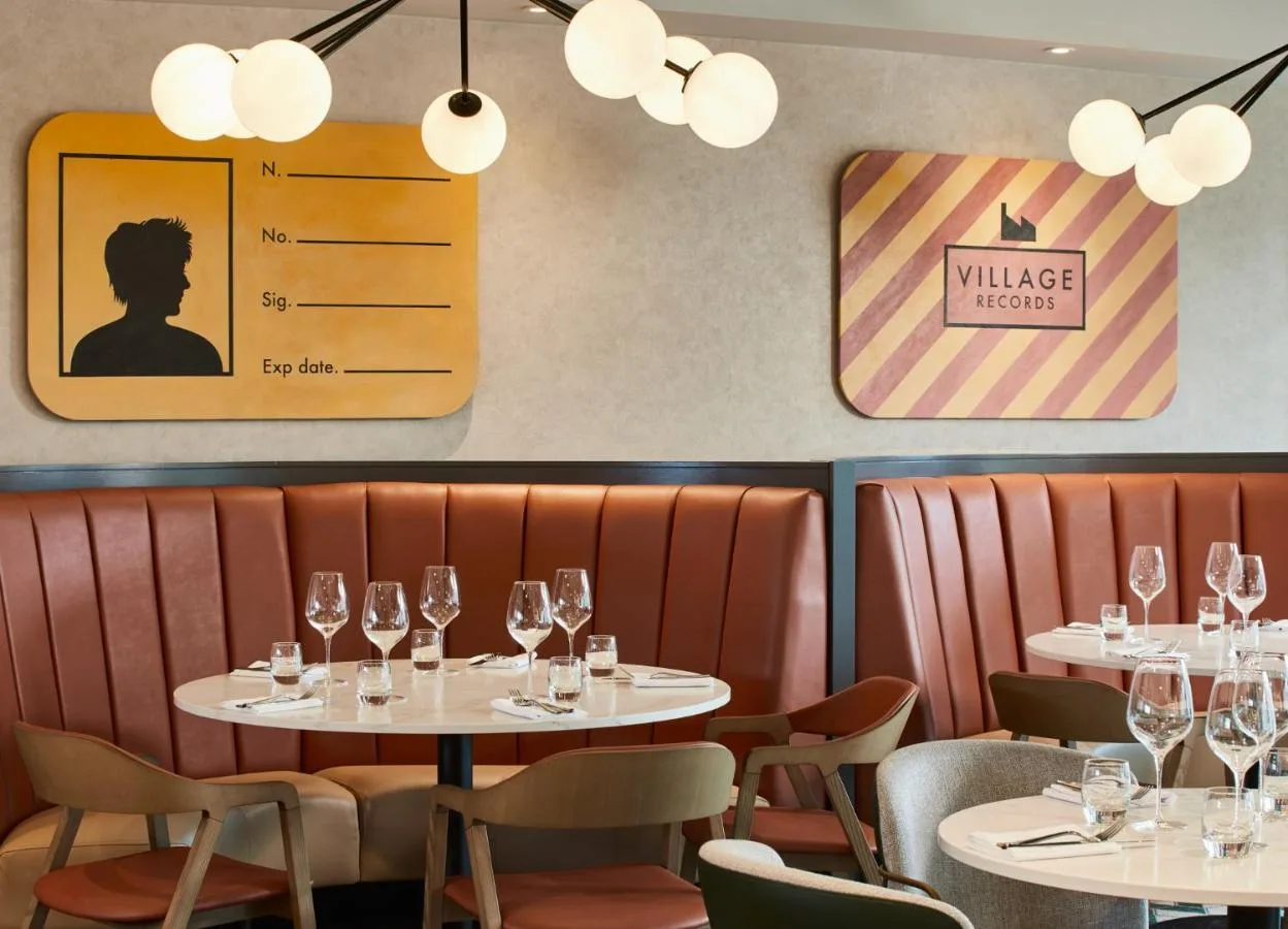 a restaurant with tables and chairs with wine glasses at Manchester Marriott Hotel Piccadilly in Manchester