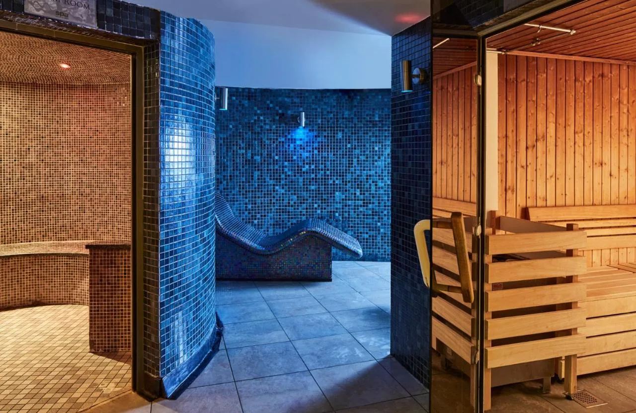 a sauna with a tub and a wooden chair at Manchester Marriott Hotel Piccadilly in Manchester