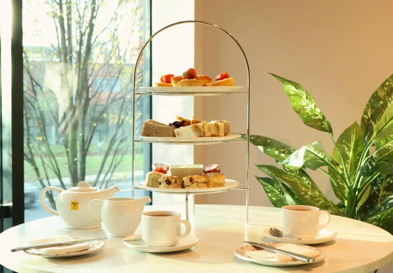 a three tiered tray with pastries and cups on a table at Manchester Marriott Hotel Piccadilly in Manchester